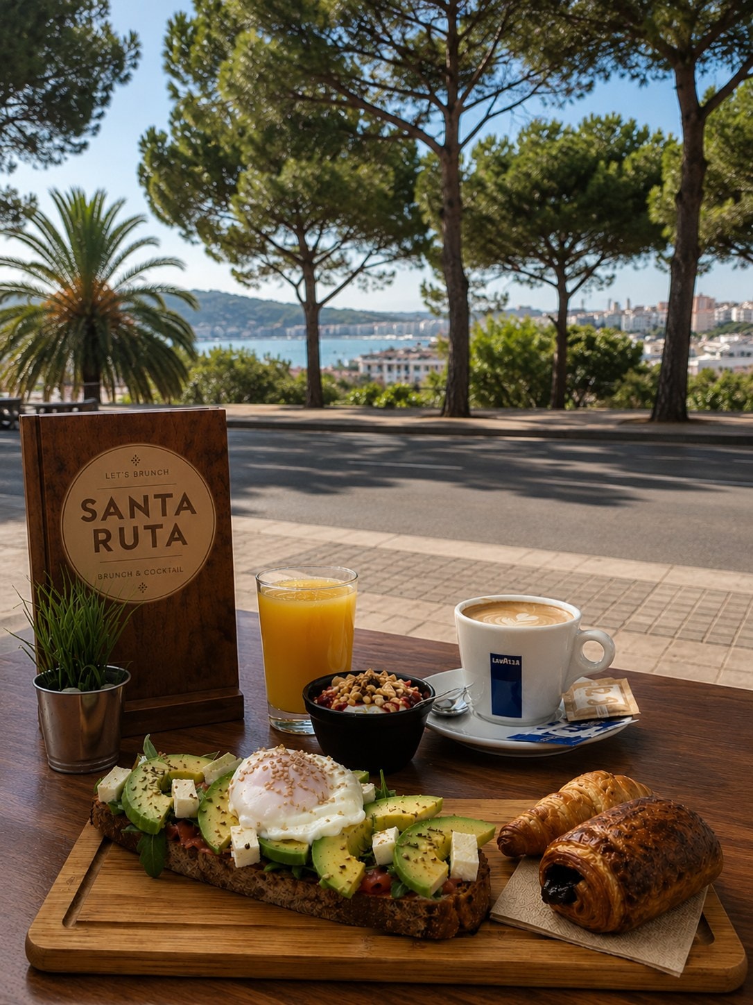 Mesa de brunch en Santa Ruta con avocado toast, café Lavazza, zumo y vistas a la bahía.